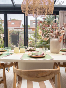 Windlichten op een gestylede buitentafel onder een overkapping bij avondlicht